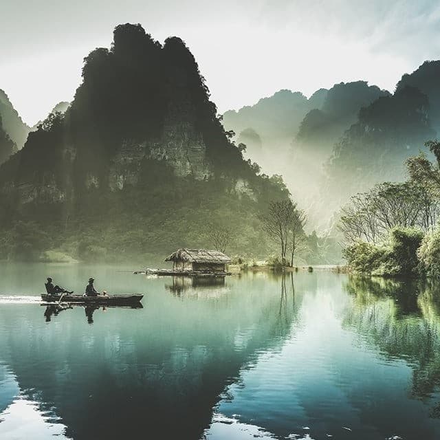 Two people on boat in middle of a lake.