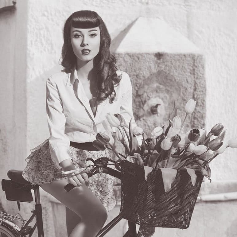 Woman on bike with flowers in it.