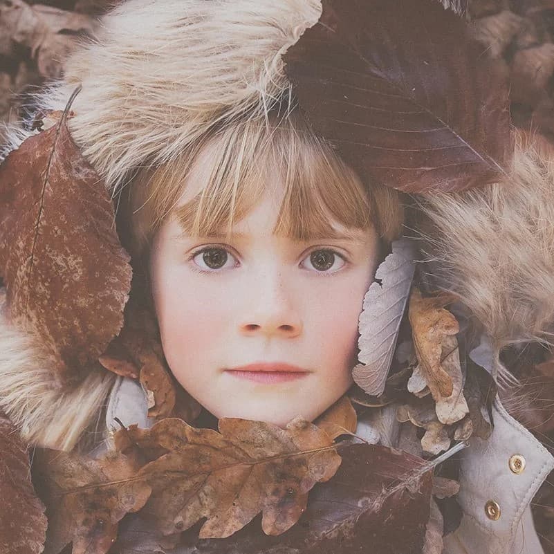 Kid face surrounded by leaves.