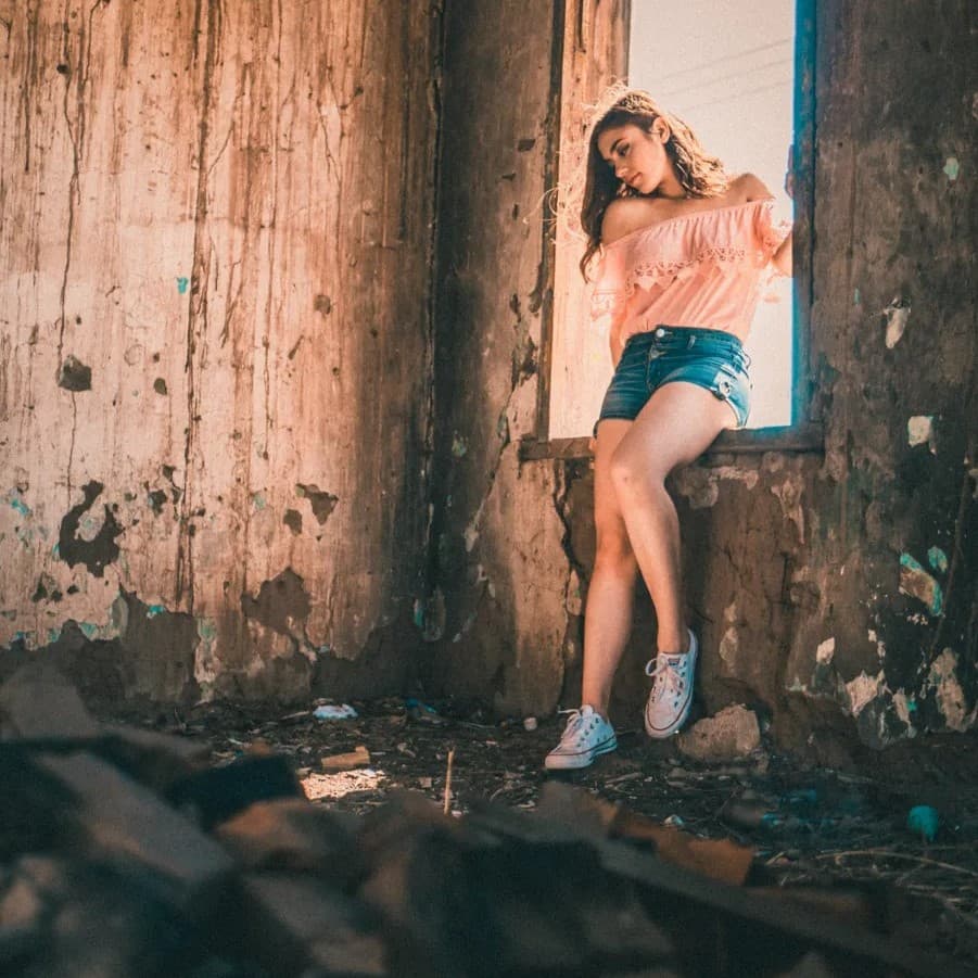 Woman standing on window sill in abandoned house.