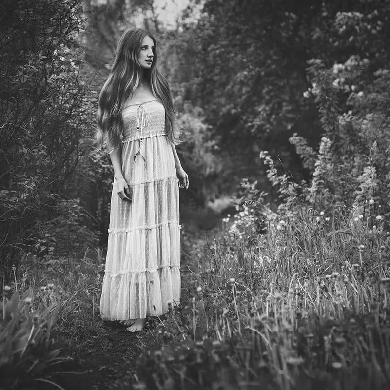 Woman in white dress standing in grass.