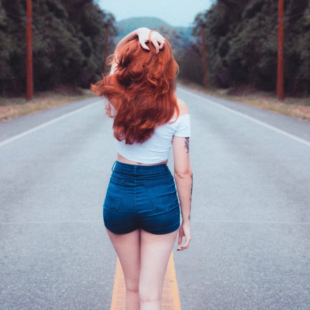 Woman walking down the line of a road.