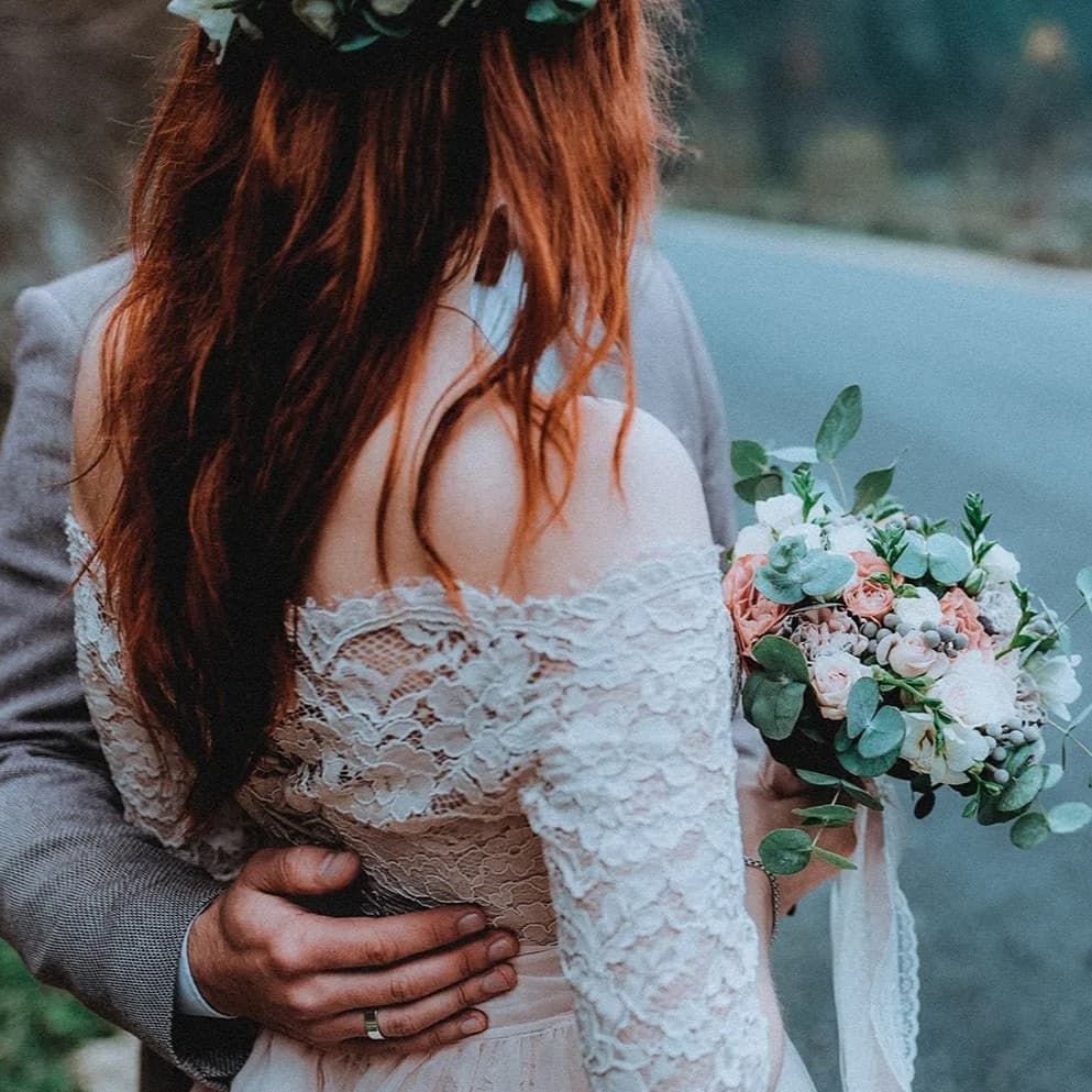 Man holding a woman with a bouquet of flowers in her hand.