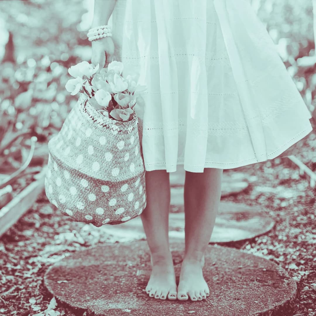 Little girl holding basket standing on stone.