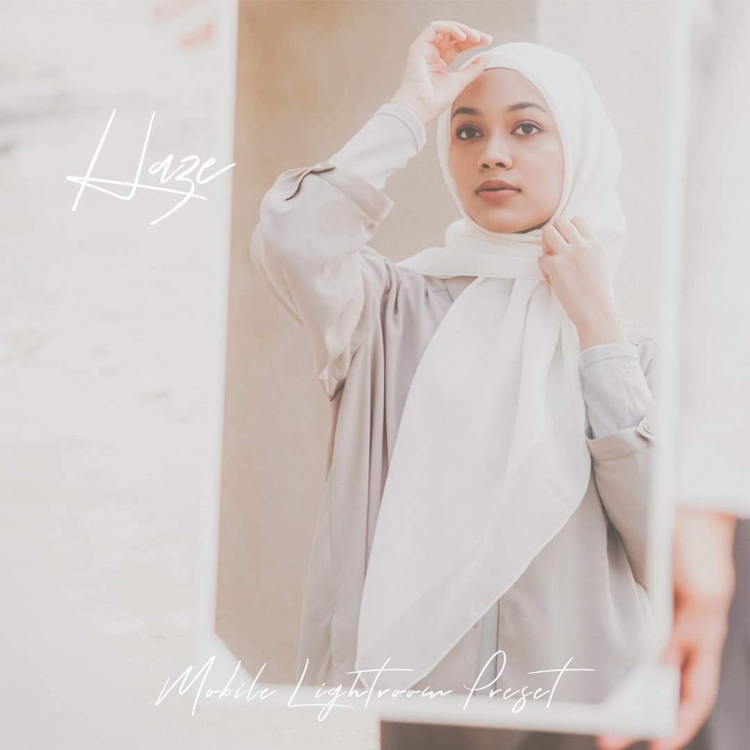 Woman standing looking at mirror while wearing a hijab.
