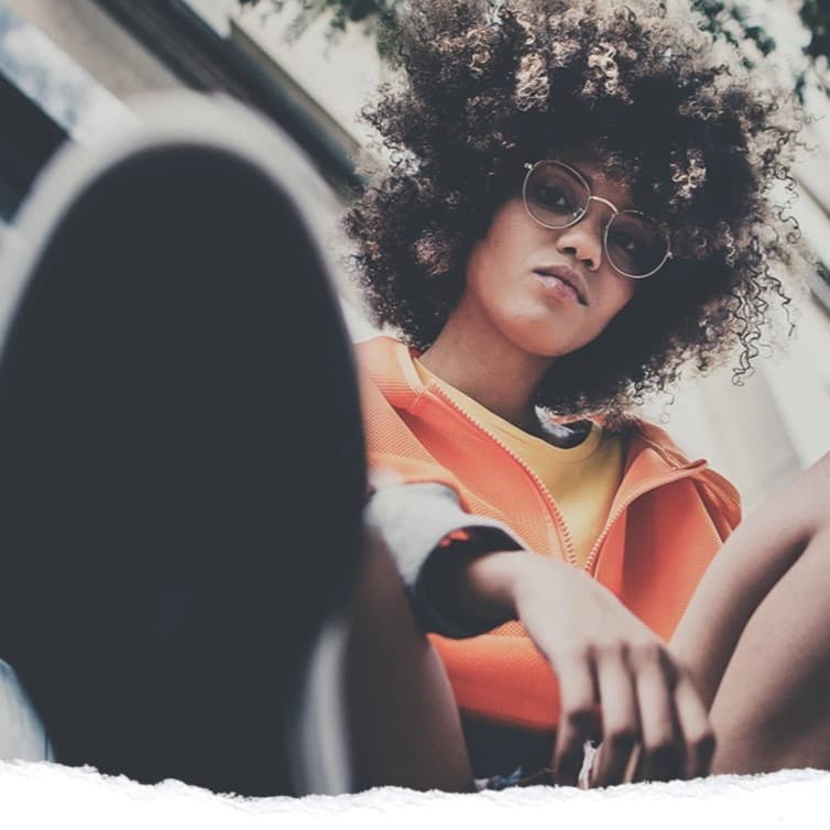 Woman sitting looking down at camera.