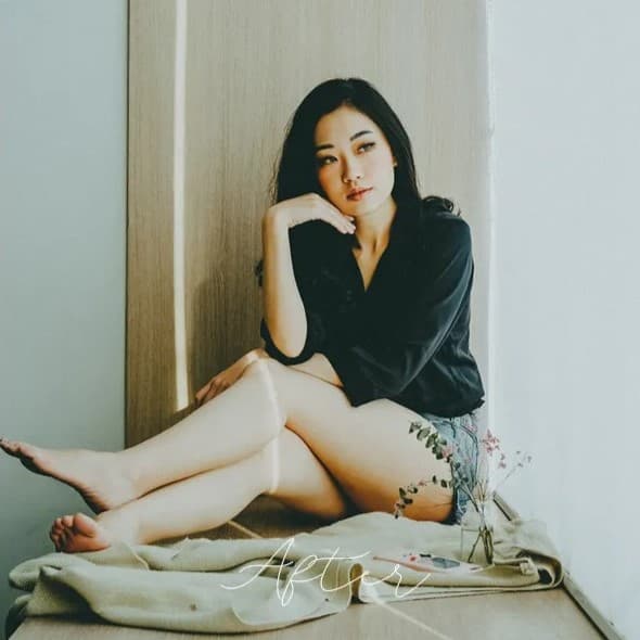 Woman sitting on bed resting.