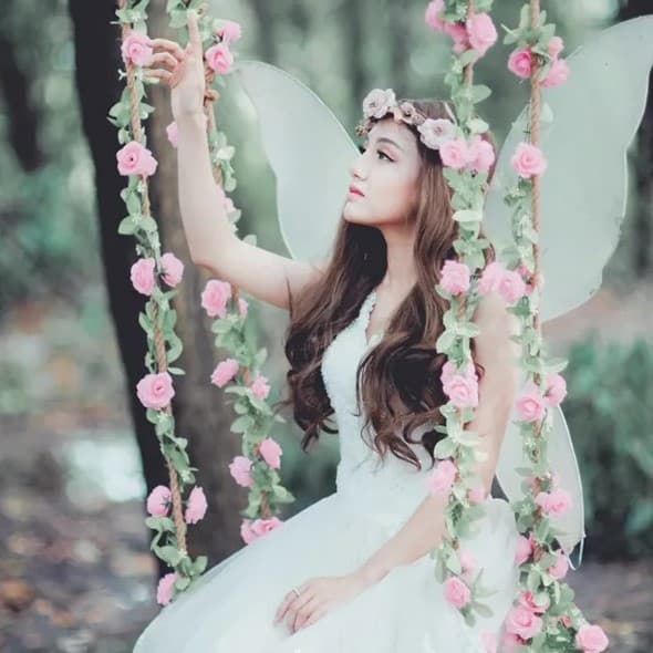 Woman sitting on flower covered swing.