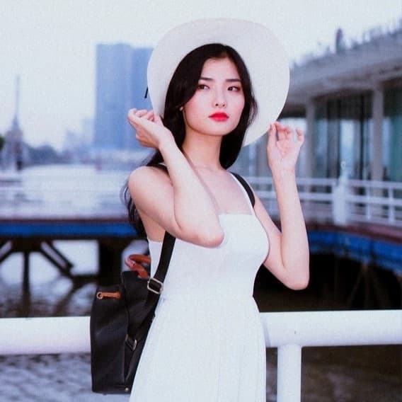 Woman wearing hat and backpack looking around.