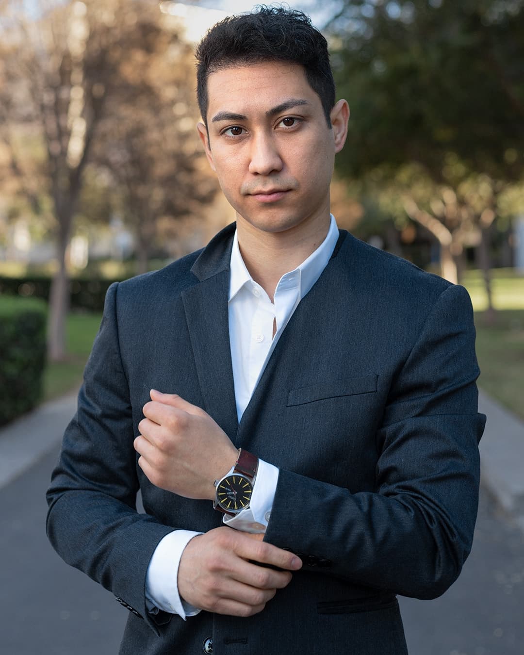 Man posing in suit adjusting his watch.