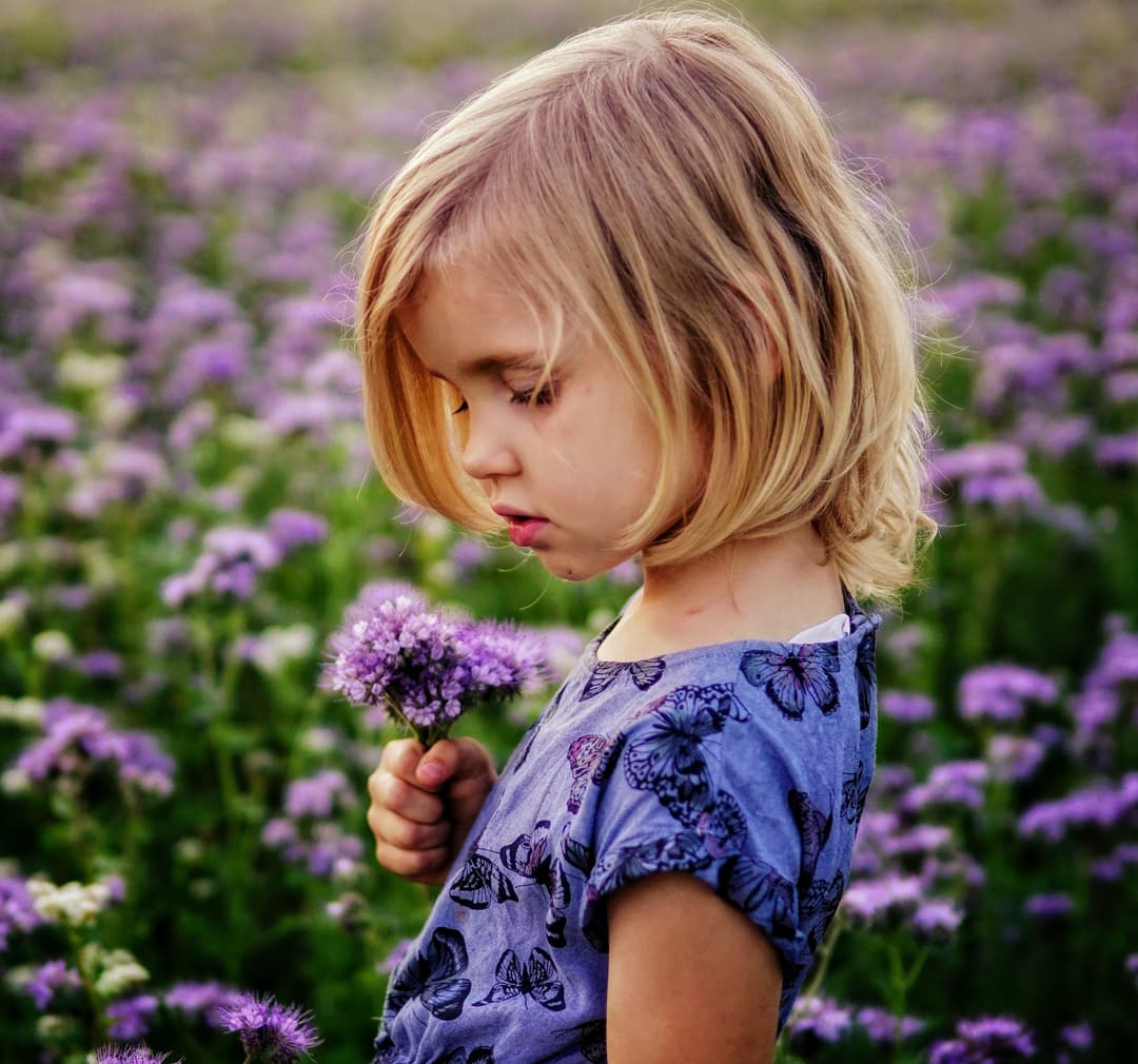 Little girl playing in flower field.