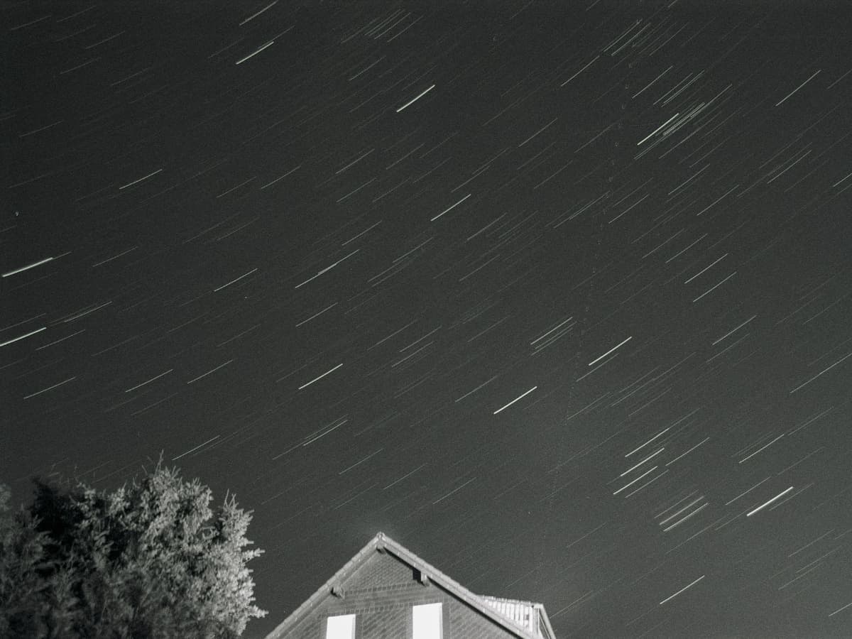 Stars in night sky by house.