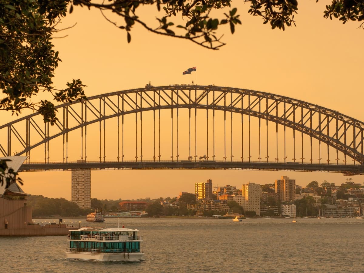 Cityscape photo with a boat on a lake with a bridge.