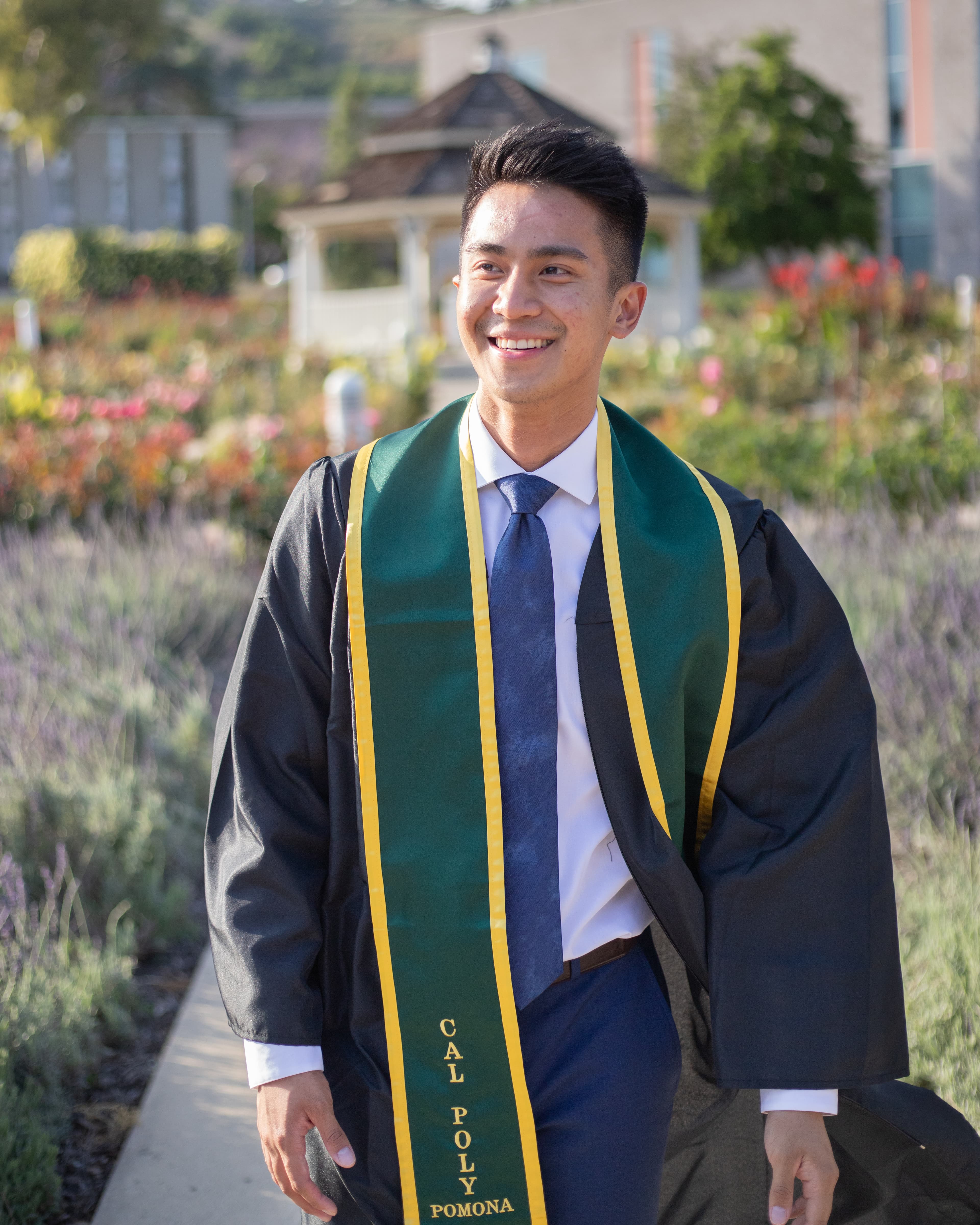 Man walking wearing Cal Poly Pomona graduation outfit.