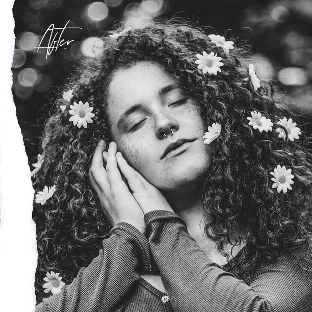 Woman with flower in hair with eyes closed.
