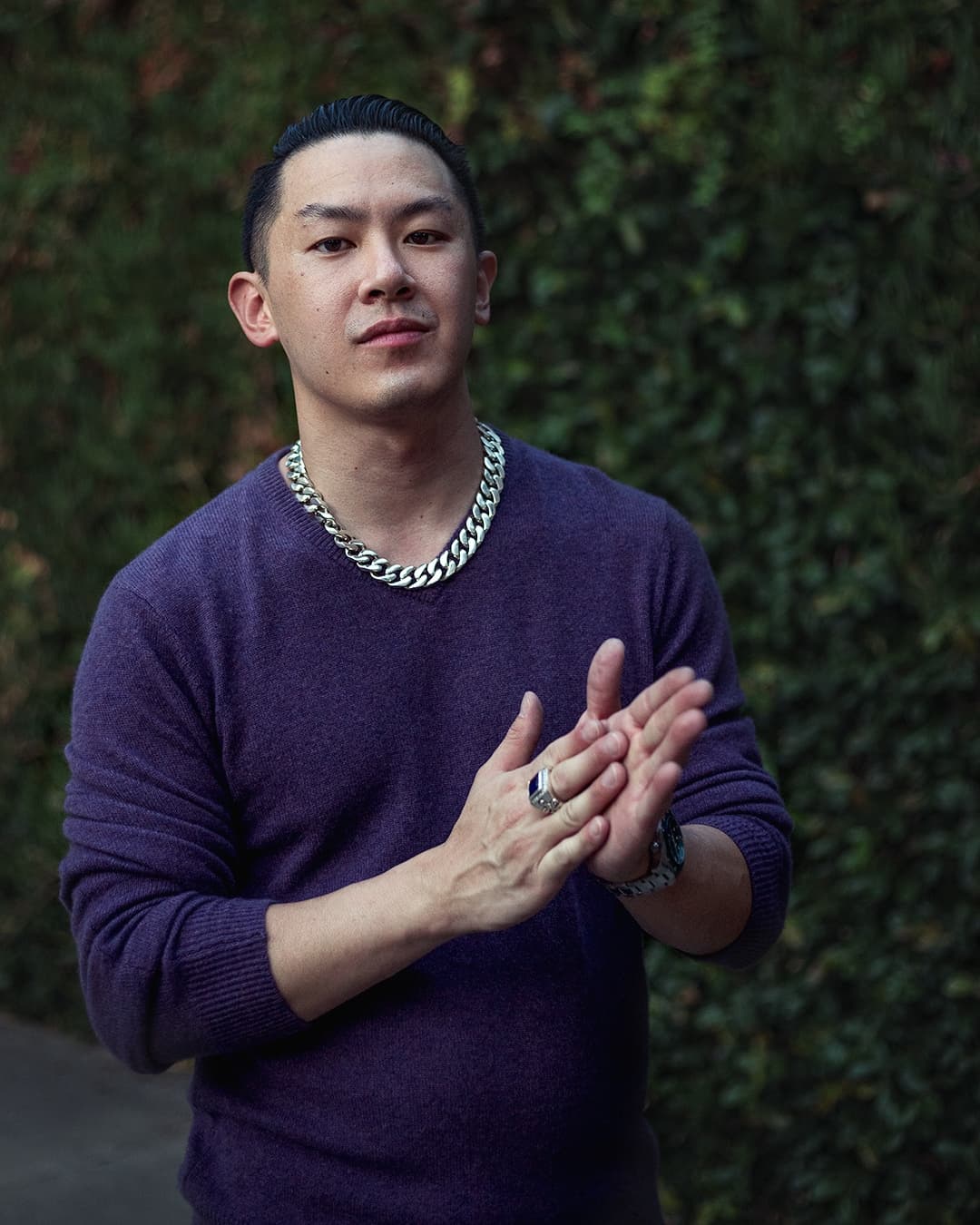 Man posing in purple sweather rubbing his hands.