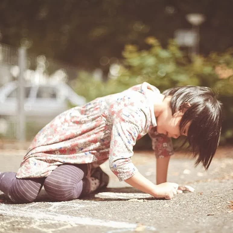 Kid writing in chalk on concrete.