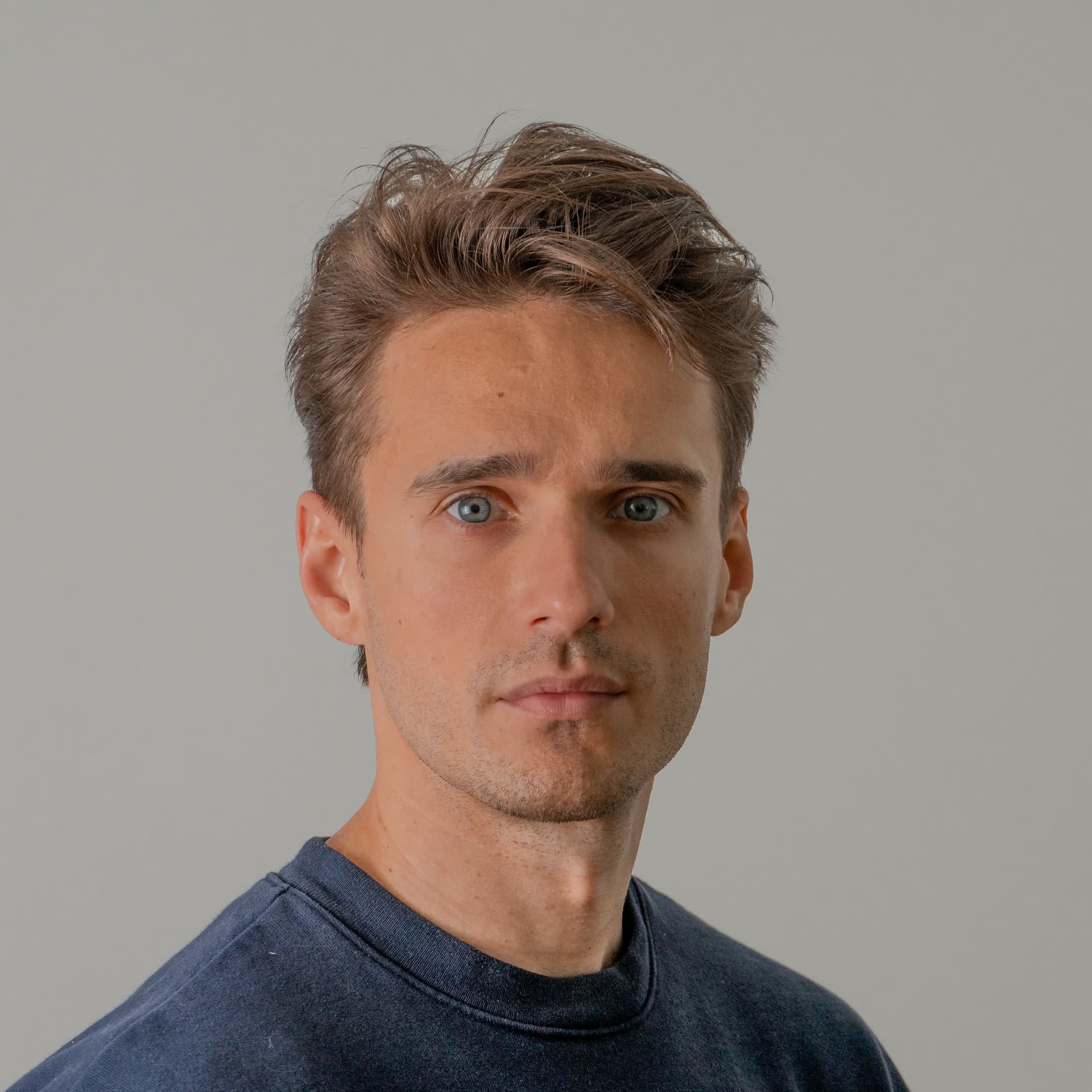 Guy looking at camera with tan background.