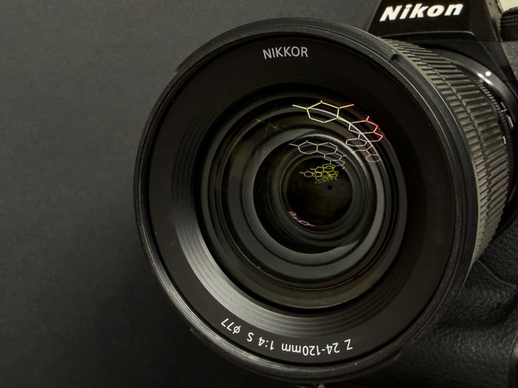 Head-on look into the large front element of the Nikon Z 24-120mm f/4 S to display the 9-blade rounded aperture mechanism