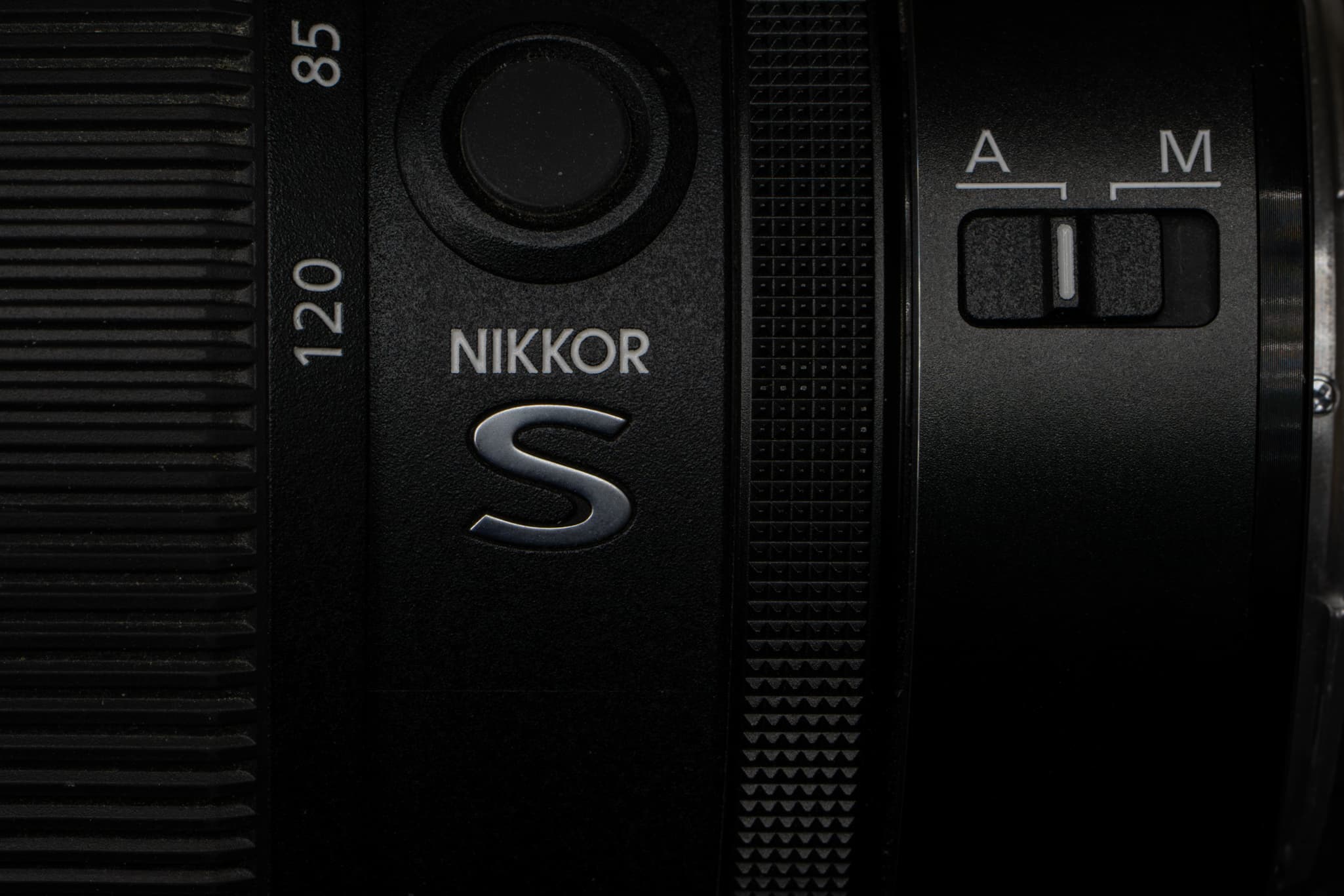 Close-up highlighting the iconic silver metallic 'S' line badge on the side of the Nikon Z 24-120mm f/4 S, emphasizing its premium tier placement