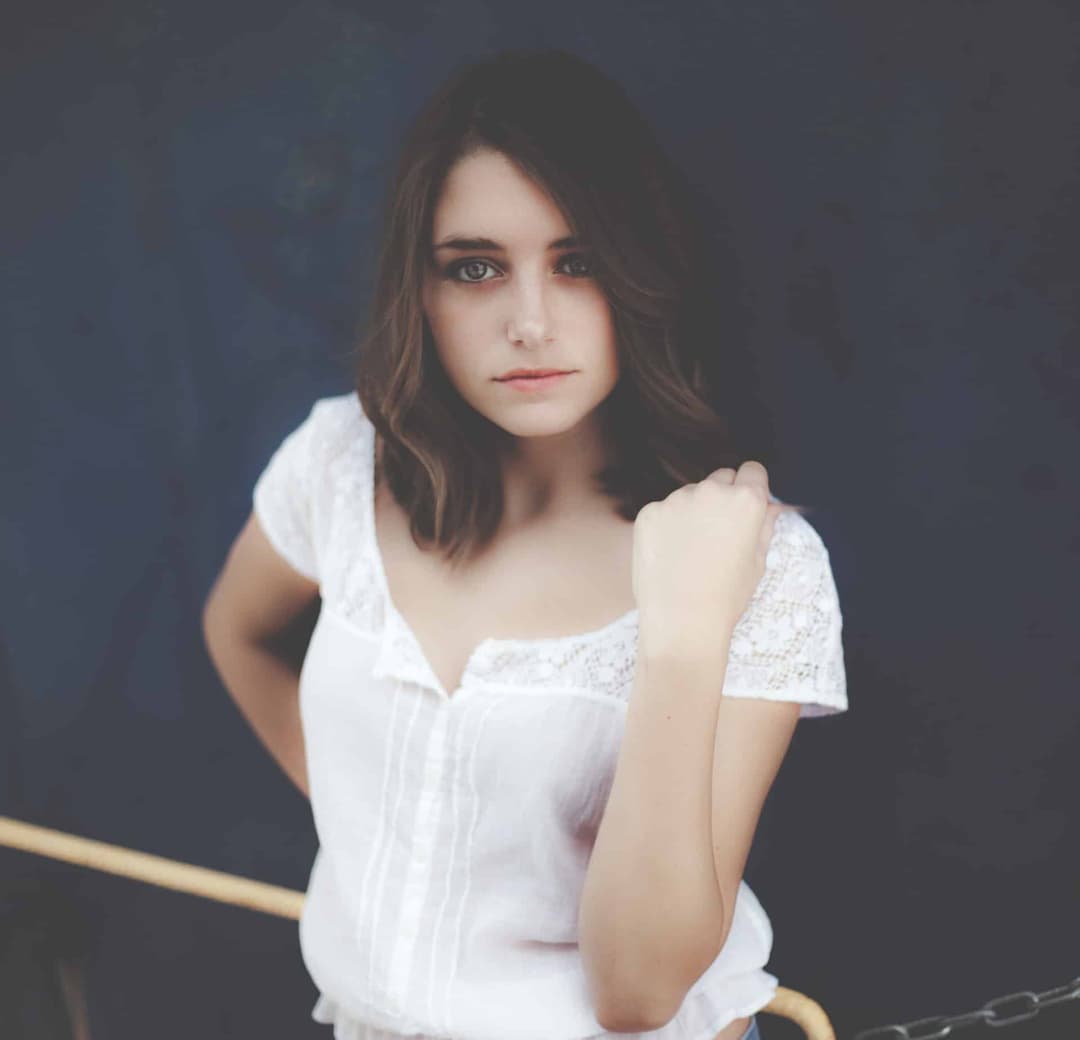 Woman looking at camera with one hand on shoulder.