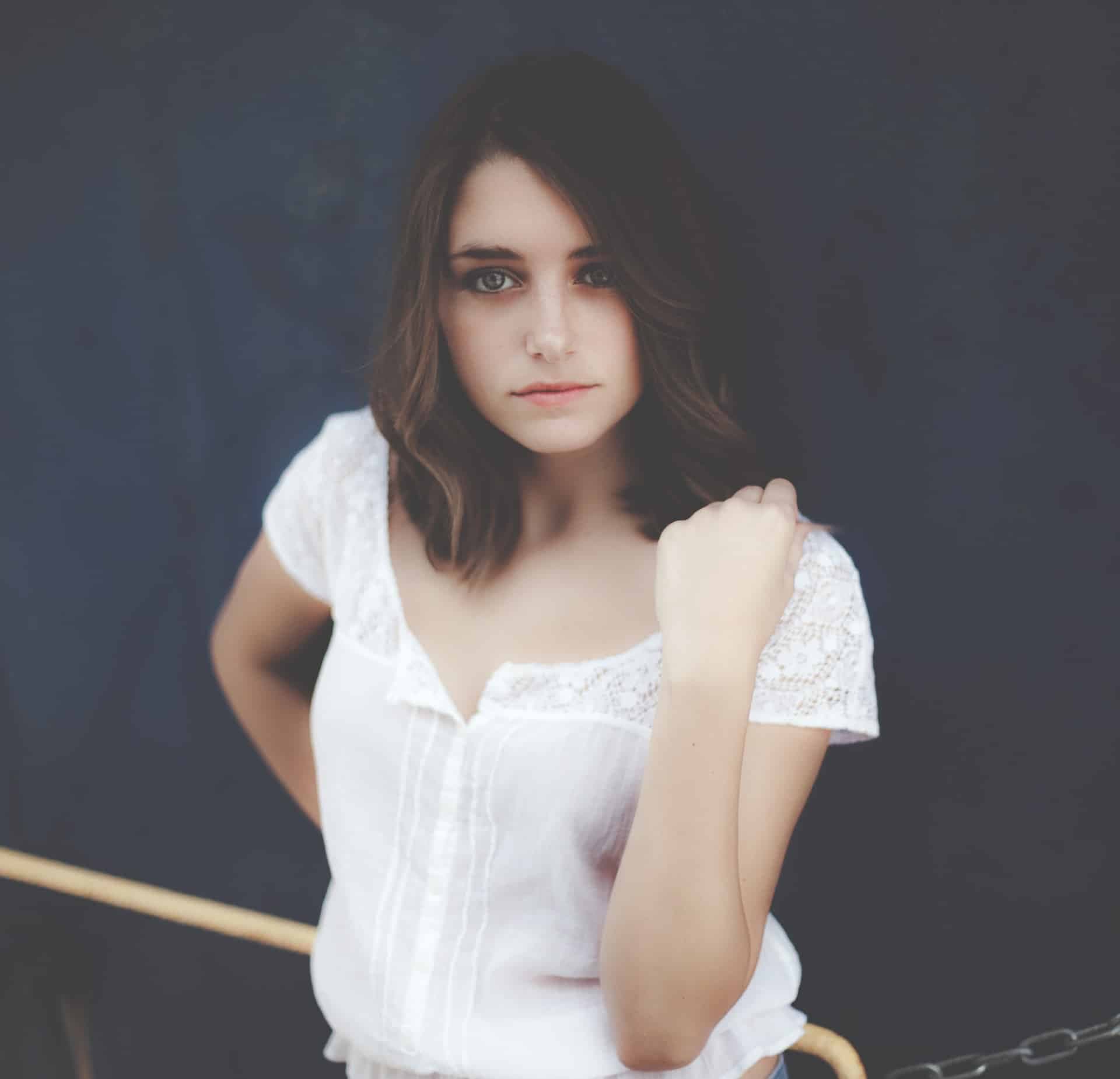 Woman looking at camera with one hand on shoulder.