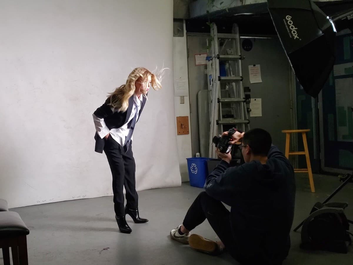 Photographer on ground photographing blonde girl in suit.