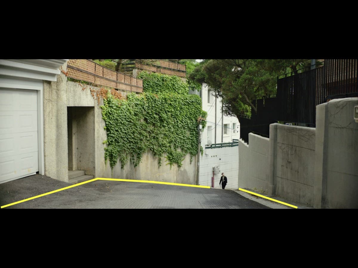 Leading lines composition from Ki-Woo walking up alley scene in Parasite.
