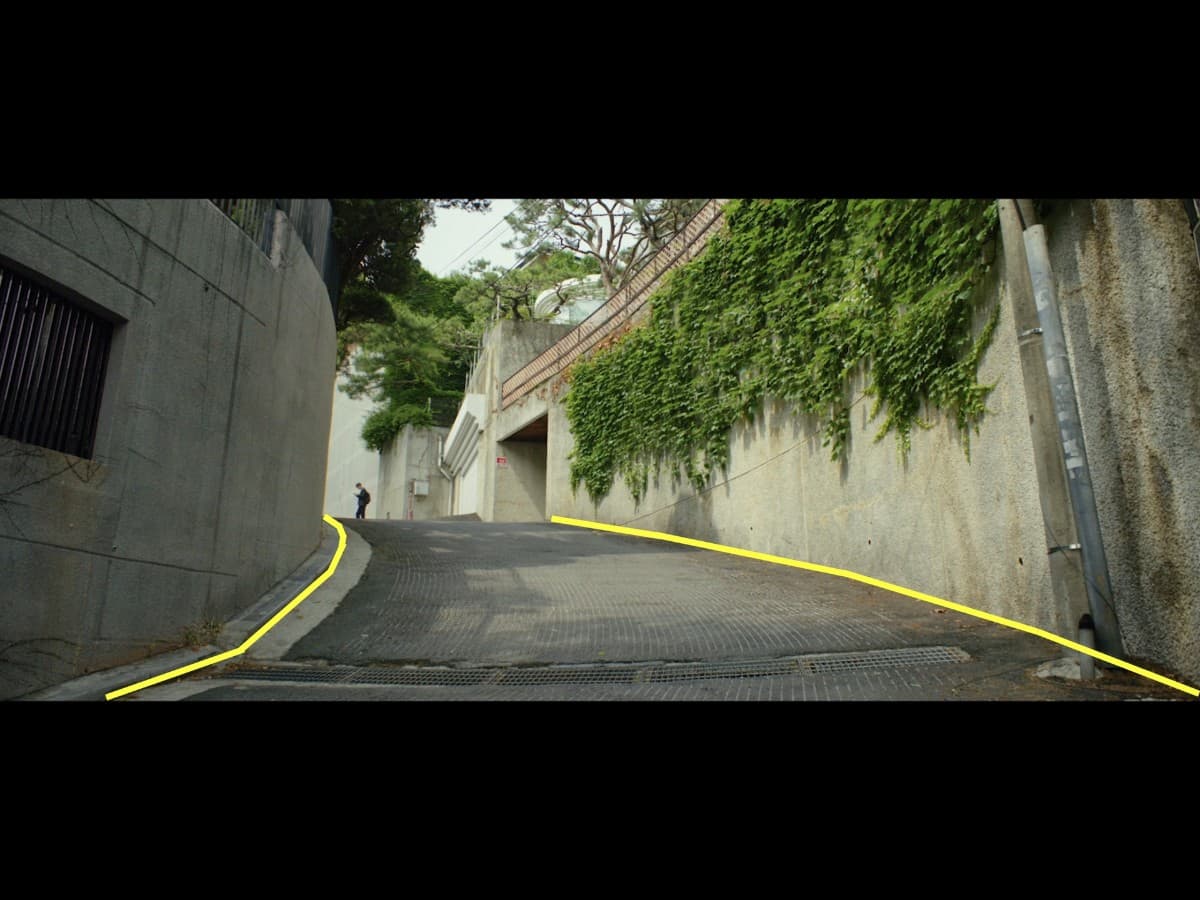 Leading lines composition from Ki-Woo walking down alley scene in Parasite.