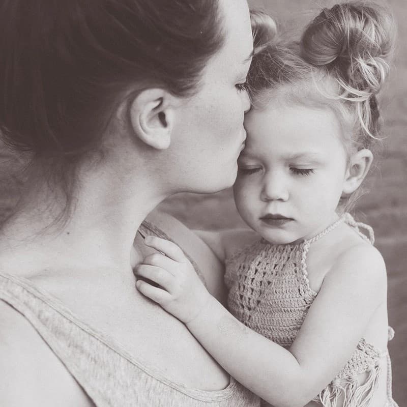 Woman kissing her child.