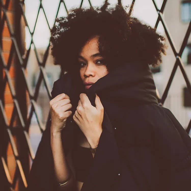 Woman wearing black hoodie on fence.