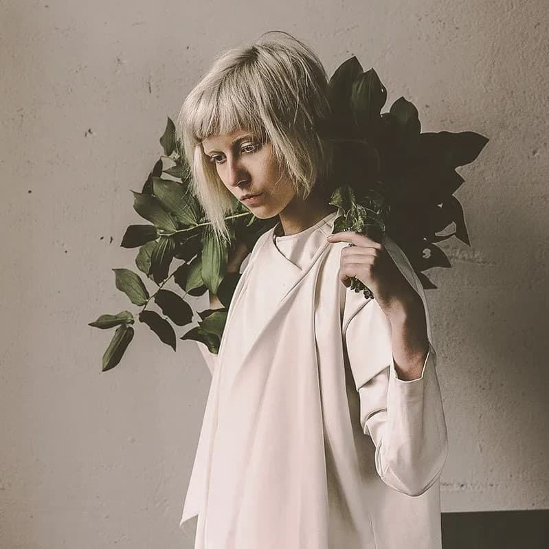 Woman holding plants over her shoulder looking down.