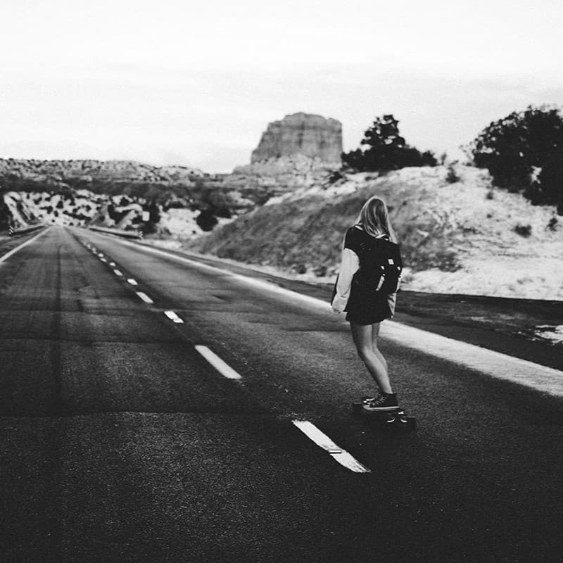 Woman skateboarding down empty street.