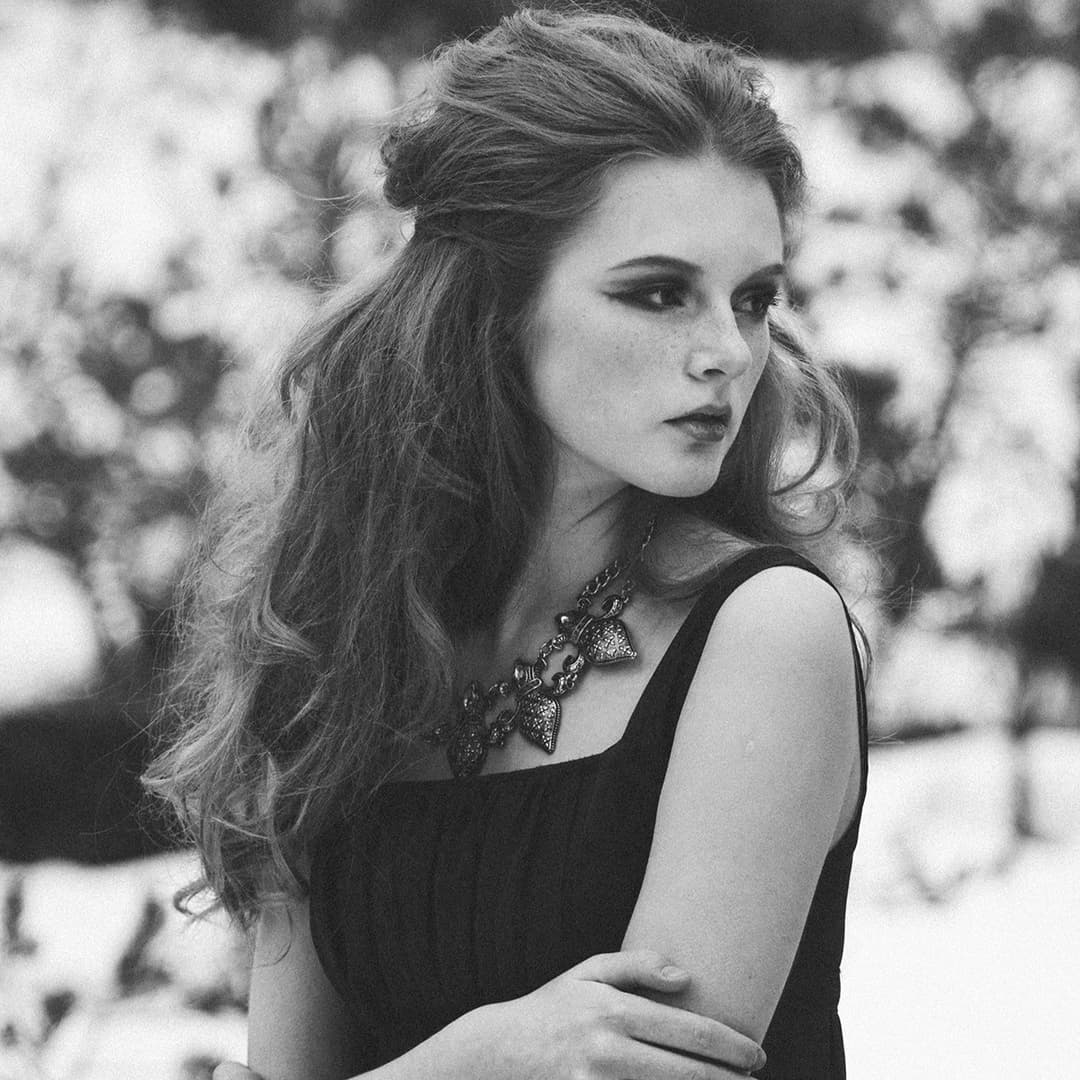 Woman looking over shoulder rubbing her arm.