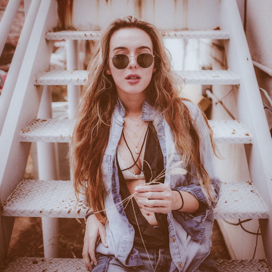 Girl sitting on stairs with sunglasses.