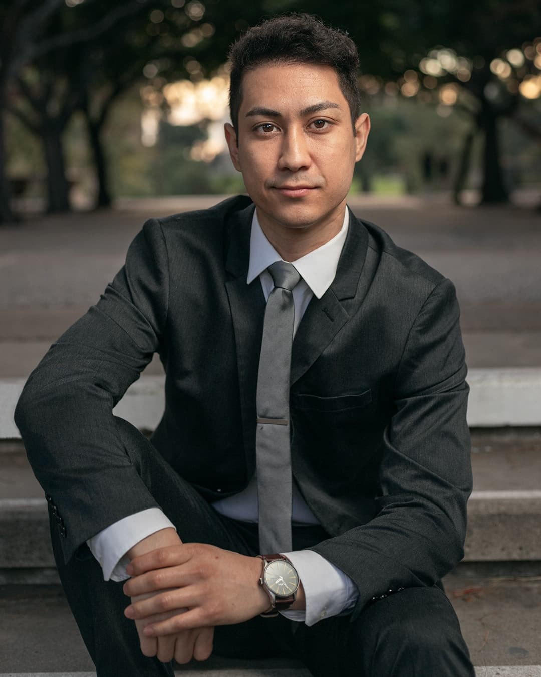 Man posing in suit sitting with staggered legs.