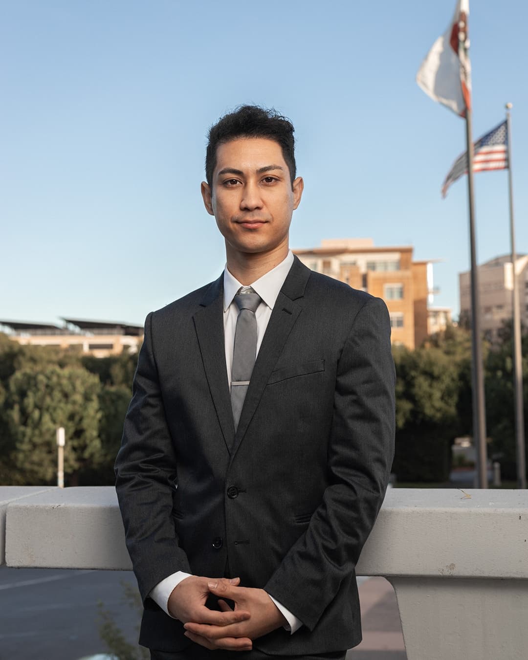 Man posing in suit standing with his hands grasped.