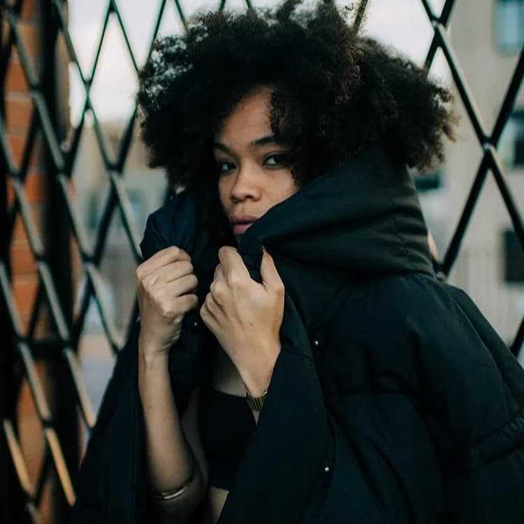 Woman wearing black hoodie on fence.