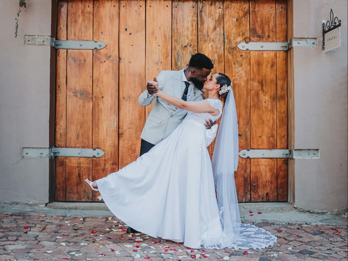 Married couple kissing in front of wooden door.