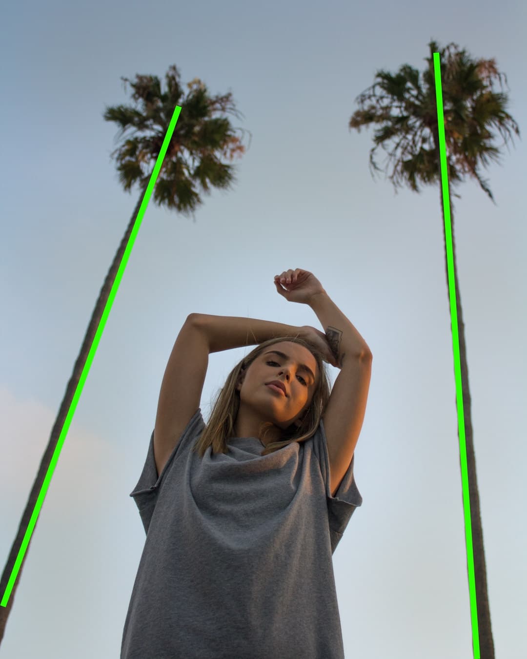 Subject framed between palm trees Girl standing with hands in air between two palm trees.