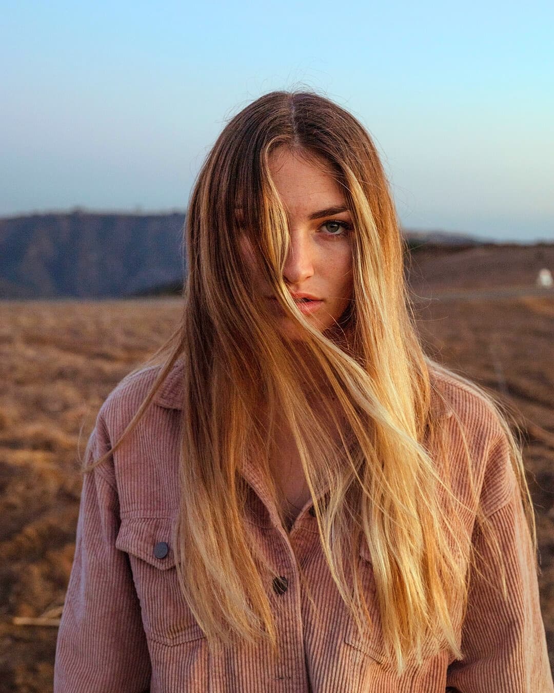 Portrait taken with natural ambient light for mysterious look Women with hair in her face on a hill during blue hour.