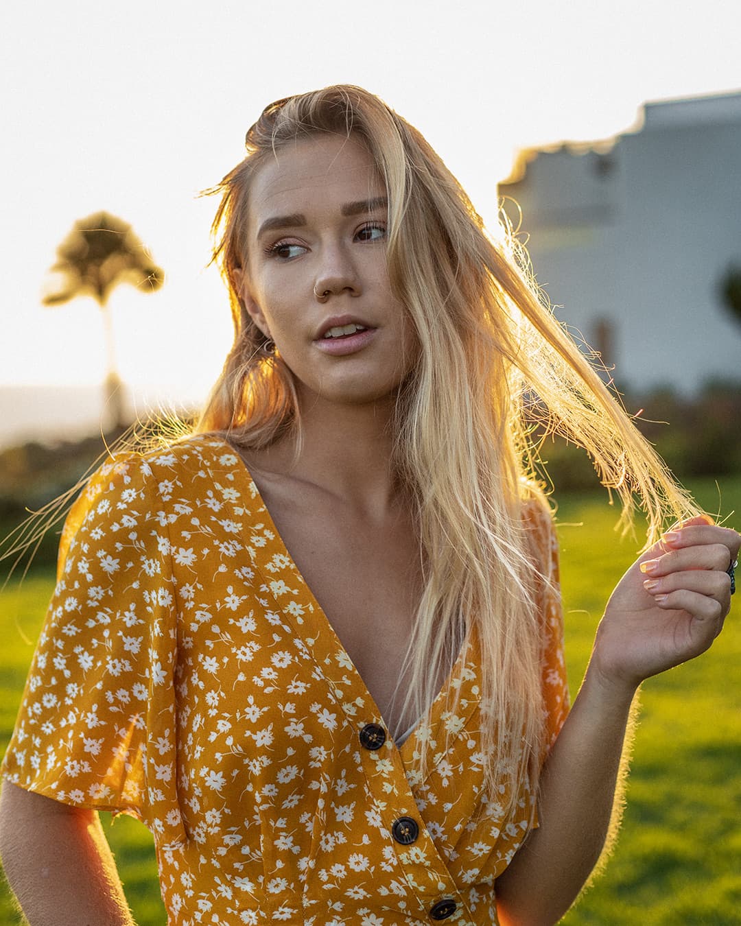 Backlit portrait during end of golden hour Girl wearing yellow dress standing in front of sun.
