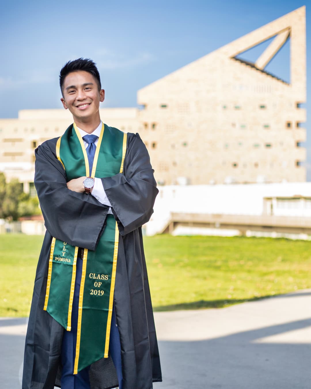 Balanced composition Man standing in graduation gown next to building.