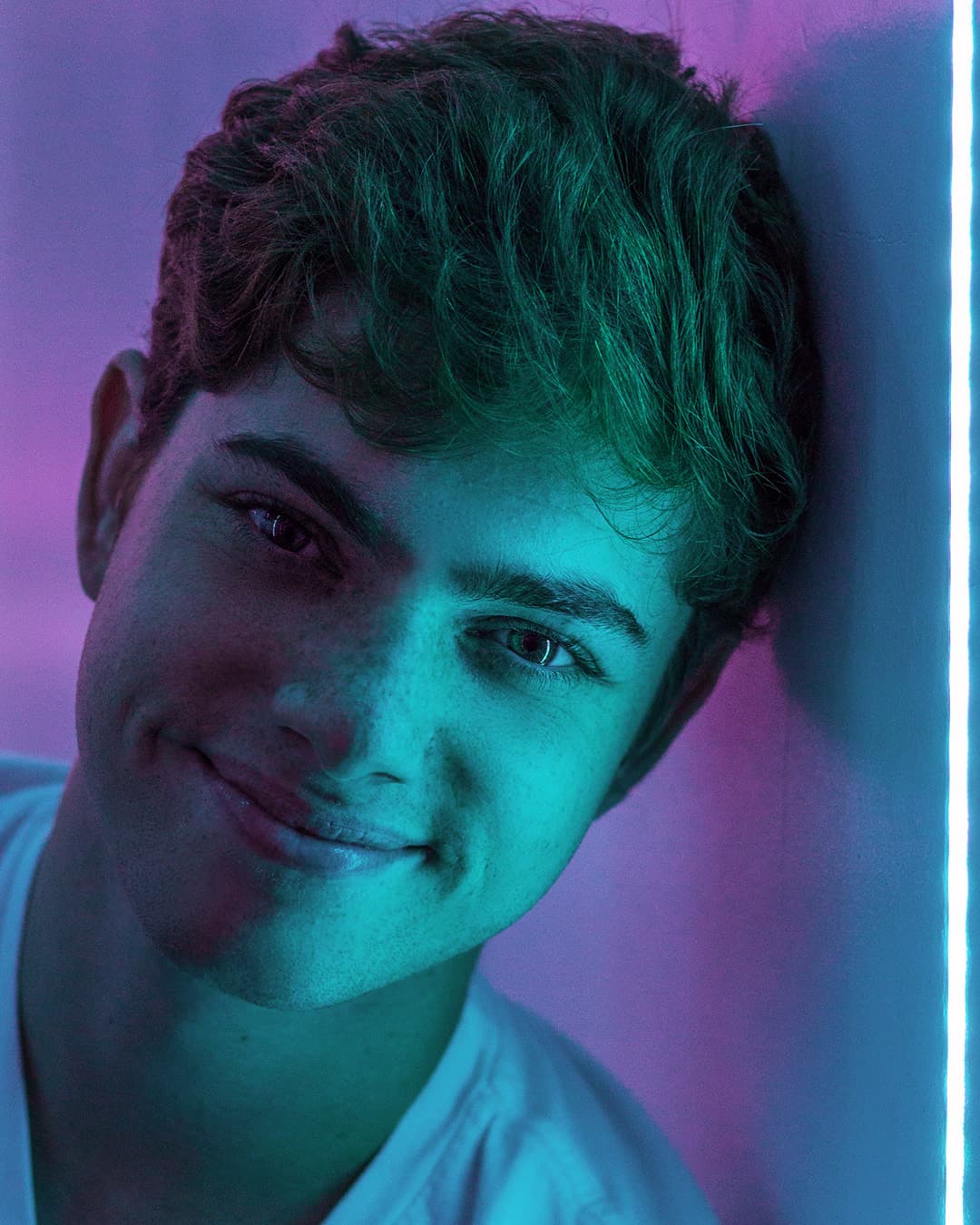 Casual headshot Man getting headshot photo taken in between two neon lights.