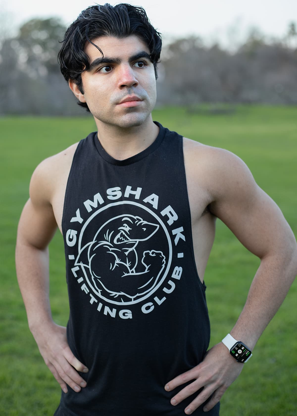 Portrait taken on cloudy day for soft light Man standing with Gymshark tanktop in a park.