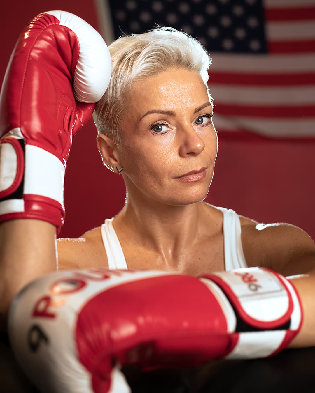 Subject being framed by her hands Woman wearing boxing gloves resting her head on one.