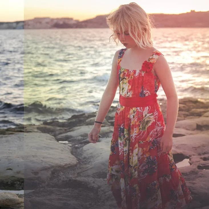 Little girl on rocks by water.