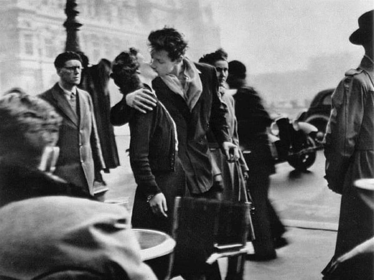 Kiss by the Hotel de Ville by Robert Doisneau Man and woman kissing on street.