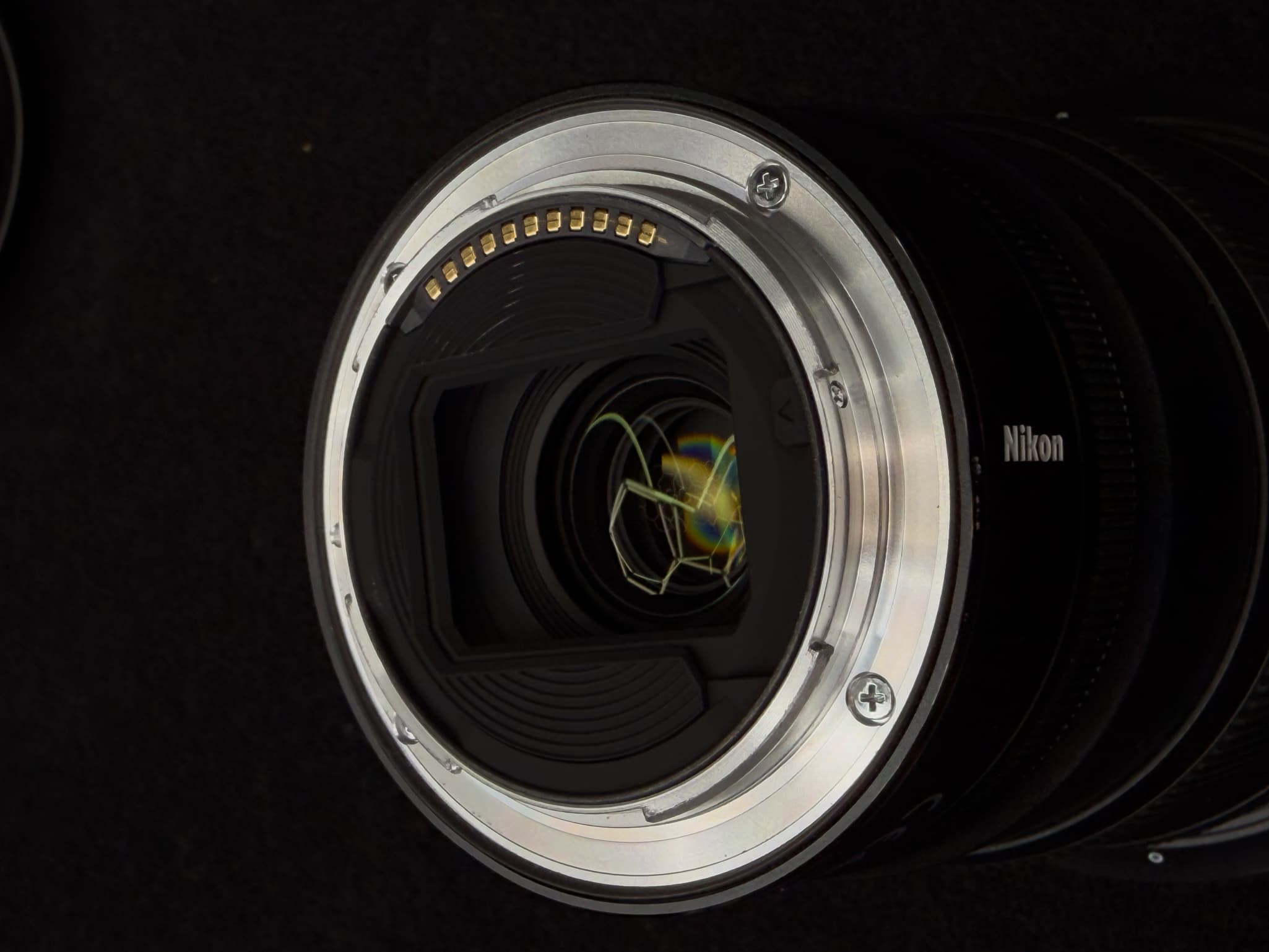 Close-up focusing directly on the thin black rubber weather-sealing gasket lining the outer rim of the rear metal mount on the Nikon Z 14-24mm f/2.8 S