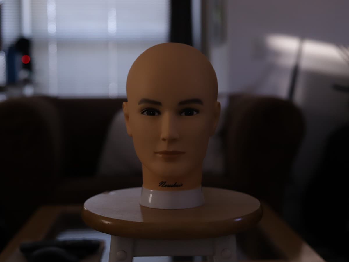 Mannequin head before bouncing the flash Dark mannequin head on a stool with minimal light on it.